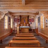 Drewniany wnętrze kościoła, ławki i ołtarz.