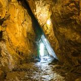 Korytarz w jaskini, widać otwór ze światłem.