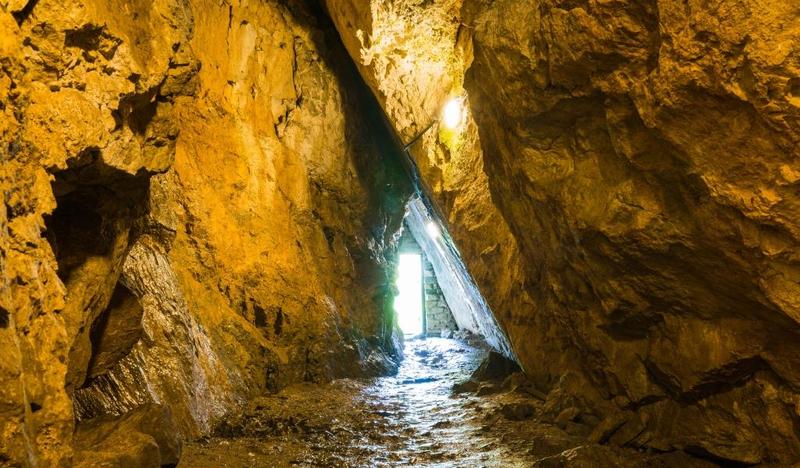 Korytarz w jaskini, widać otwór ze światłem.