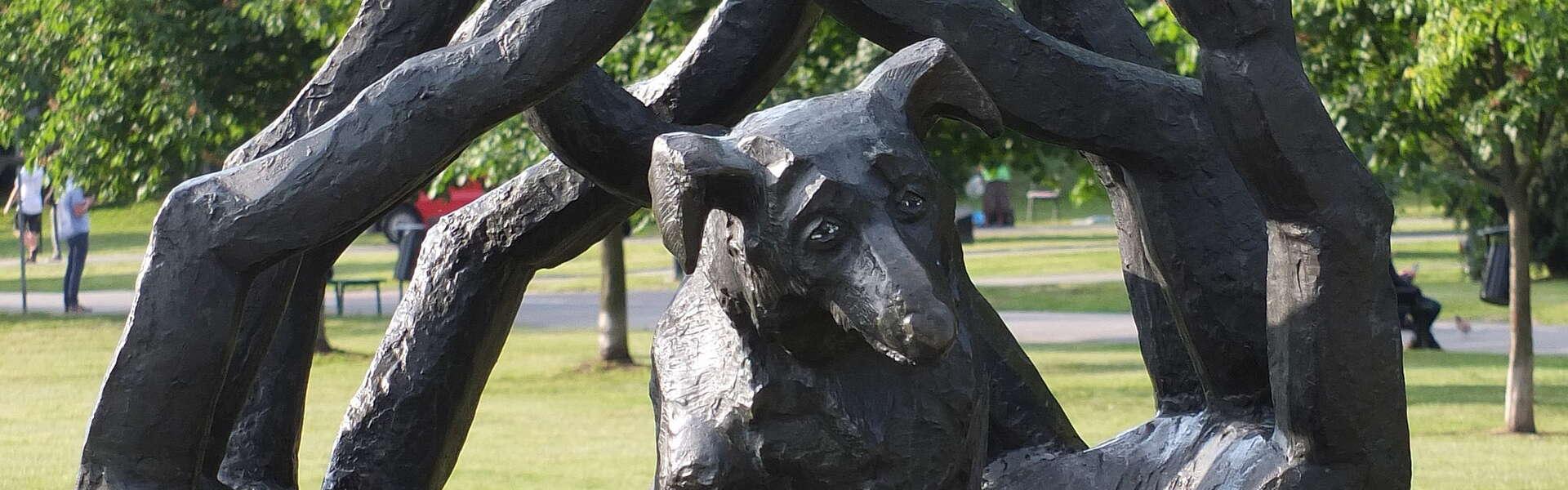 Pomnik na którym widać siedzącego psa z wyciagniętą łapą