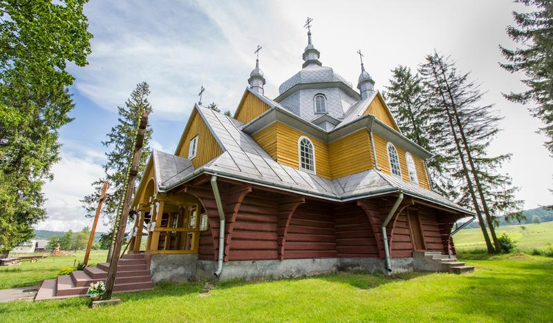 Drewniana cerkiew na planie krzyża greckiego, zwieńczona kopułą, drewniana, częściowo pomalowana na żółto.