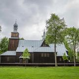 Drewniany kościół z wieżą i dachem pokrytym jasną blachą. Wokół kościoła niskie drewniane ogrodzenie.