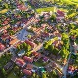Panorama Lipnicy Murowanej z drona. Widać duży rynek, odchodzące od niego uliczki i ulice obwodowe tworzące owalnicę, ładne domy, dużo zieleni.