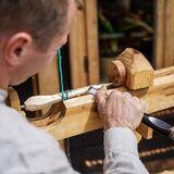 Mężczyzna przy drewnianej tokarce tworzy przedmiot z drewna