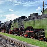 tory, po lewej czarna lokomotywa, za nią zielony skład z węglarką.