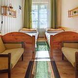 Pokój jest ułożony symetrycznie. Zarówno po lewej jak i prawej stronie na dole stoją sofy, następnie pojedyncze łóżka, a nad łóżkami wiszą półki z lapkami. Na środku pokoju ułożone są małe dywany. Na wprost znajduje się okno z firanką i zielonymi zasłonami.