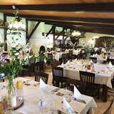 sala z drewnianym sufitem i elegancko nakrytymi kwadratowymi stołami ozdobionymi kwiatami