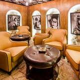 Skórzane, duże fotele wokół dwóch stolików na sali cigar room w restauracji Enoteka Pergamin w Krakowie. Na stołach popielniczki, a na ścianach czarno-białe zdjęcia  kobiet.