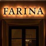 Widok na oświetlony szyld Restauracji Farina w Krakowie wieczorową porą.