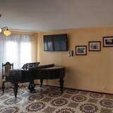 Salon z fortepianem, na ścianach zdjęcia.