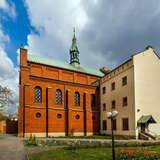 Kościół pw. Niepokalanego Serca Maryi w Krakowie z zewnątrz. Widać dwie części świątyni, jedna ceglana, a druga gładka beżowa. Budynek jest otoczony murem, a koło niego znajduje się ogród z kwiatami.