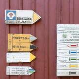Drogowskazy turystyczne na ścianie schroniska PTTK na Leskowcu oraz tablica informacyjna o szlakach