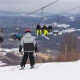 Młody narciarz na stoku Laskowa-Ski. W tle widać rozmazany wyciąg narciarski krzesełkowyoraz wzgórza.