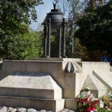 Pomnik - wzniesienie z kamieni zwieńczone czarną metalową urną postawioną na czterech metalowych słupkach. Pod pomnikiem kwiaty.
