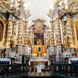 Wnętrze kościoła z ołtarzem głównym i ołtarzami bocznymi, bogato zdobione i złocone.