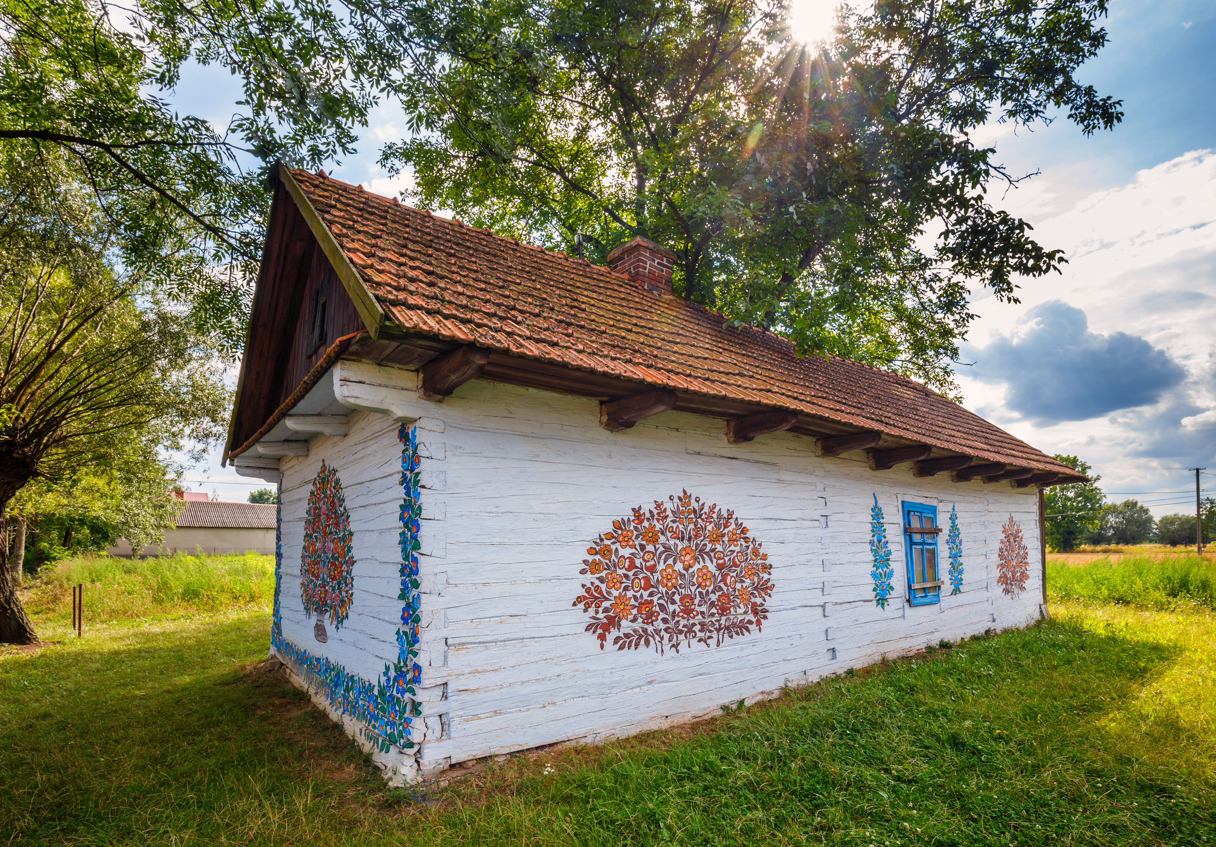 Biała chata z wymalowanym na ścianach kolorowym bukietem 